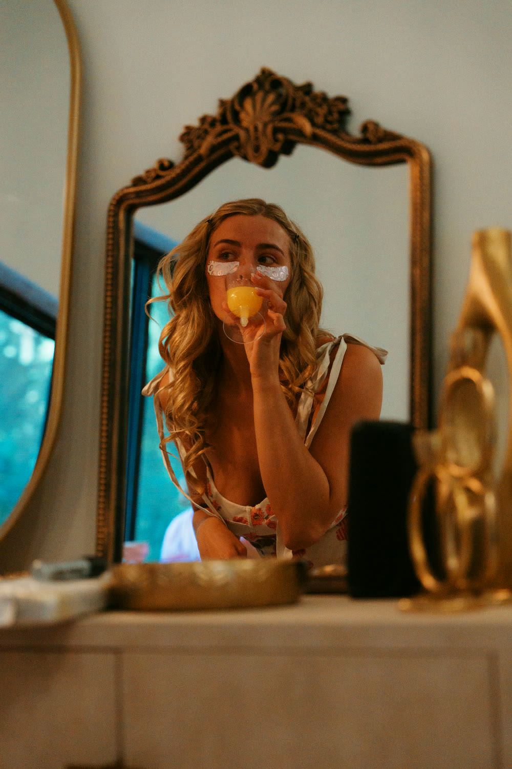 A bride reflected in a gold mirror in the guest suite on the morning of